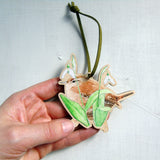 small wooden decoration of a watercolour illustration of a Eurasian wren amidst some snowdrop flowers