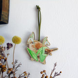 wooden hanging decoration with a wren and snowdrops illustration in green and brown